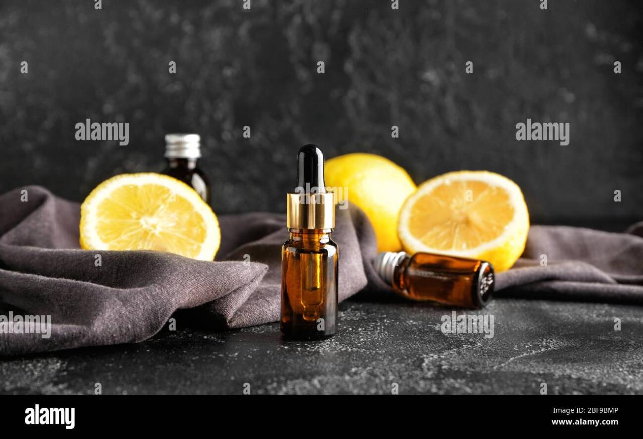 Premium Photo | Bottle of essential oil with lemon on wooden background
